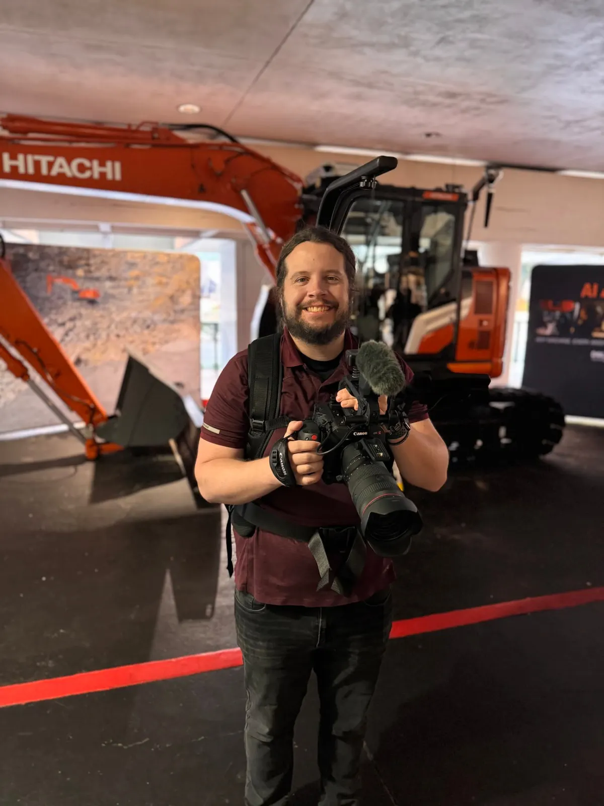 Camera operator with heavy equipment at a trade show